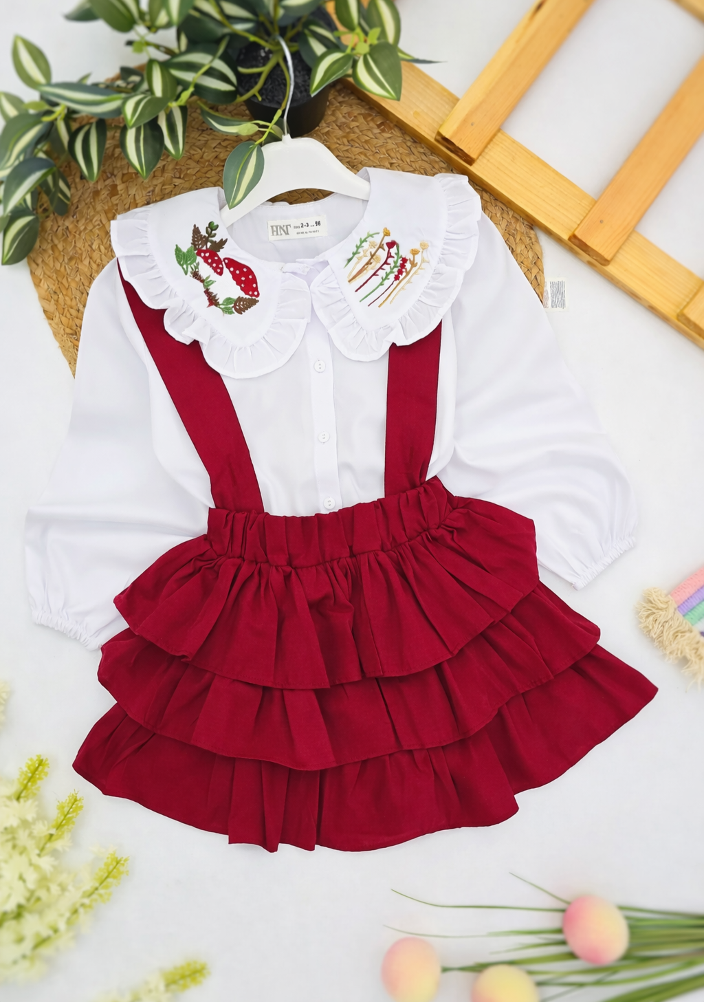 Bela košulja i tamno crvena suknjica sa tregerima i karnerima